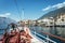 Boat tour: Boat bow with boat bell, view over azure blue water, mountain range and little village. Lago di Garda, Italy