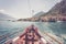 Boat tour: Boat bow, view over azure blue water, village and  mountain range. Lago di Garda, Italy