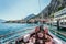 Boat tour: Boat bow, view over azure blue water, village and  mountain range. Lago di Garda, Italy