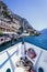 Boat tour: Boat bow, view over azure blue water, village and  mountain range. Lago di Garda, Italy