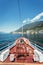 Boat tour: Boat bow, view over azure blue water, village and mountain range. Lago di Garda, Italy