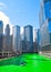 Boat travels across a Chicago River is dyed green for St. Patrick`s day as crowds surround scene.