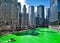 Boat travels across the Chicago River which is dyed green for St. Patrick`s day as crowds surround scene.