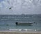 Boat waiting on beach front for kite surfers, with wispy blue sky and surfer in background