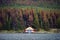 Boathouse with canoe on pier in autumn pine forest on hill in Maligne lake