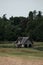 Boathouse next to Meadow and Forest with two people in the background