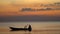 The boatman in the Vietnamese hat in the small boat. The man fishes at sunset. Close up. Silhouette at sunset.View from