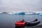 Boats on the beach coast of black sand volcanic rock stones in glacier lagoon Fjallsarlon mountains and glacier lagoon on the