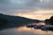 boats behid hill at lake windermere during sunset in the lake district