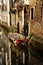 Boats covered from rain parked in the water next to the house in canal of Venice.