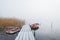 Boats at a frosty wooden jetty in a misty lake in Sweden.