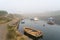 Boats in heavy sea fret at the harbour, at high tide in Seaton Sluice, Northumberland, UK