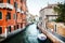 Boats moored between colorful houses and walking couples. Canals in Venice, Italy