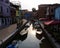 Boats moored in the navigable canal of Burano island near Venice