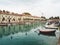 boats are parked along the shore at a pier with many small buildings in the background