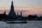 Boats sail on the Chao Phraya river in the late evening. Wat Arun Temple stands on the river