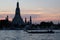 Boats sail on the Chao Phraya river in the late evening. Wat Arun Temple stands on the river