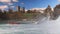 Boats for tourists float near the Rhine Falls with spray against the old town in Switzerland