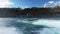 Boats for tourists float near the Rhine Falls with spray against the old town in Switzerland