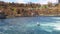 Boats for tourists float near the Rhine Falls with spray against the old town in Switzerland