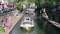 Boats traveling sailing down a canal in an urban environment with trees in the