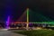 Bob Kerrey pedestrian bridge Omaha Nebraska at night with purple, yellow and green lights reflections in Missouri river.