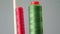 A bobbin of red and green cotton thread on the spindle of the sewing machine in the foreground, close-up. sewing factory