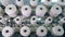 Bobbins with threads rotate on a rack at a textile plant. Industrial fabric production line.