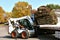 Bobcat lifts a pallet of sod rolls from a semi trailer