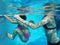 Bodies of mother and small daughter swimming in a pool under water. Woman and girl. Blue color