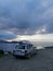 Bodrum, Turkey - 23 December 2022: A silver Dodge Caravan minivan type car with a surf on roof stands on the seashore