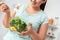 Body Care. Chubby girl standing in kitchen eating green salad close-up blurred background smiling joyful
