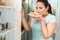 Body Care. Chubby girl standing in kitchen near fridge holding plate with doughnuts and cheesecake smelling joyful close