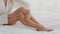 Body Care Concept. Closeup of unrecognizable young lady applying moisturising lotion on legs