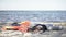 Body of dead woman lying on seashore near life jackets, shipwreck victim