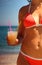 Body of girl in swimsuit. She holds glass of juice