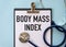 BODY MASS INDEX text on a card clip to a notepad on a table