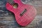 Body of a pink ukulele lying on a wooden surface