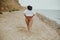 Body positive. Plus size boho girl in white shirt running on sunny beach, back view. Carefree stylish big woman relaxing on