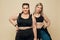 Body Positive. Plus Size Models Portrait. Blonde And Brunette Women In Sport Clothes On Beige Background.