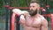 Bodybuilder demonstrates muscles. Young bearded athletic bodybuilder plays sports outdoors