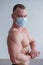 Bodybuilder with a naked torso in a medical mask. Muscled with a guy doing sports in quarantine. Respiratory protection.