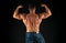 Bodybuilder perfect shape rear view. Strong bodybuilder flexing arms muscles black background. Fit bodybuilder showing