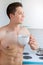 Bodybuilder young man daydreaming future shirtless drinking coffee in the kitchen portrait format