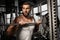 Bodybuilding. Bearded man standing at gym with barbell looking aside curious