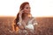 Boho chic style. Portrait of bohemian girl with white art posing over wheat field enjoying at sunset. Outdoors photo. Tranquility