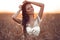 Boho chic style. Portrait of bohemian girl with white art posing over wheat field enjoying at sunset. Outdoors photo. Tranquility