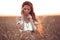 Boho chic style. Portrait of bohemian girl with white art posing over wheat field enjoying at sunset. Outdoors photo. Tranquility