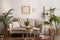 Boho and cozy interior of living room with design beige sofa, pillows, mock up poster frames, rattan coffee tables, plants, bamboo