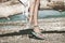 Boho girl wearing jewelry on feet and flip flop sit on  dried tree on the beach summer day close up